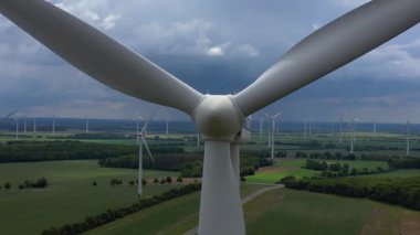 Rüzgar türbinleri Almanya 'da bulutlu bir gökyüzünün altında büyük bir rüzgar parkında temiz enerji üretiyor. Uç uç ters uçuşu kapat 