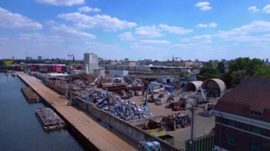 Metal bir hurdalığın havadan görünüşü, işçilerin bir şehrin yakınındaki geri dönüşüm amacıyla atık maddeleri sınıflandırdığını ve yönettiğini gösteriyor. statik üç ayaklı insansız hava aracı 