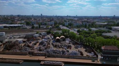 Metal bir hurdalığın havadan görünüşü, işçilerin bir şehrin yakınındaki geri dönüşüm amacıyla atık maddeleri sınıflandırdığını ve yönettiğini gösteriyor. panorama genel görünüm dronu 