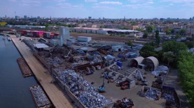 Metal bir hurdalığın havadan görünüşü, işçilerin bir şehrin yakınındaki geri dönüşüm amacıyla atık maddeleri sınıflandırdığını ve yönettiğini gösteriyor. Yukarıdan insansız hava aracı görüntüleri 