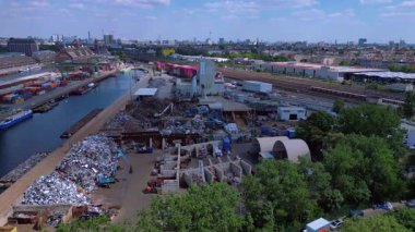 Metal bir hurdalığın havadan görünüşü, işçilerin bir şehrin yakınındaki geri dönüşüm amacıyla atık maddeleri sınıflandırdığını ve yönettiğini gösteriyor. Yukarıdan insansız hava aracı görüntüleri 