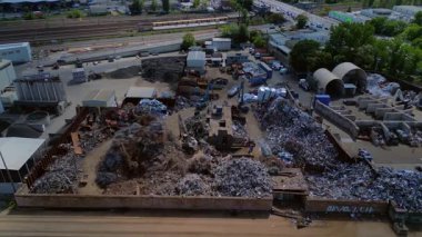 Metal bir hurdalığın havadan görünüşü, işçilerin bir şehrin yakınındaki geri dönüşüm amacıyla atık maddeleri sınıflandırdığını ve yönettiğini gösteriyor. Yukarıdan insansız hava aracı görüntüleri 