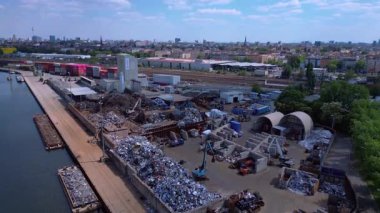 Metal bir hurdalığın havadan görünüşü, işçilerin bir şehrin yakınındaki geri dönüşüm amacıyla atık maddeleri sınıflandırdığını ve yönettiğini gösteriyor. İHA alçalıyor 