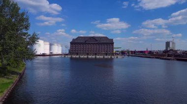 Berlin Westhafen endüstriyel limanının arka planında yakıt depolama tankları, kargo konteynerleri ve Berlin şehir manzarası var. Ters İHA uçuşu 