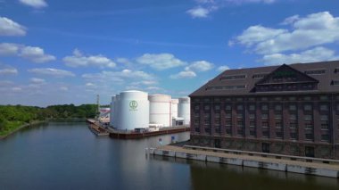 Berlin Westhafen endüstriyel limanının arka planında yakıt depolama tankları, kargo konteynerleri ve Berlin şehir manzarası var. Dolly sol İHA 