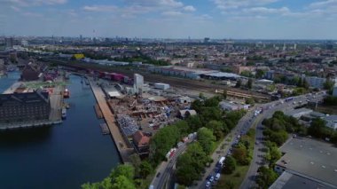 Berlin Westhafen endüstriyel limanının arka planında yakıt depolama tankları, kargo konteynerleri ve Berlin şehir manzarası var. panorama genel görünüm dronu 