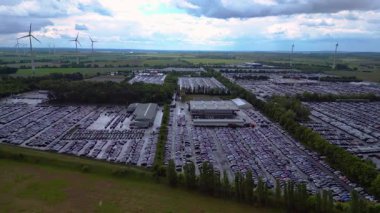 Bir rüzgar çiftliği ve Almanya 'nın kırsal kesiminin yakınındaki bir araba dolu büyük bir otoparkın havadan görüntüsü. Sinek yağmur dronunu ileri it 