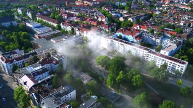 Sarı kurtarma helikopteri dumanlı bir acil durum sırasında Berlin şehir parkına iniyor. Yukarıdan insansız hava aracı görüntüleri 
