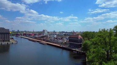 Hurda metal geri dönüşüm fabrikasının nehir limanındaki atıkları yöneten, mavnaları yükleyen hava görüntüsü. İHA yükseliyor 