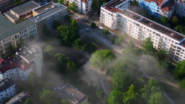 Sarı kurtarma helikopteri dumanlı bir acil durum sırasında Berlin şehir parkına iniyor. İHA kamerası aşağıya bakıyor 