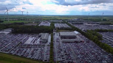 Bir rüzgar çiftliği ve Almanya 'nın kırsal kesiminin yakınındaki bir araba dolu büyük bir otoparkın havadan görüntüsü. panorama görünümü yağmur dronu 