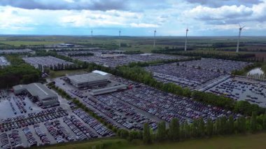 Bir rüzgar çiftliği ve Almanya 'nın kırsal kesiminin yakınındaki bir araba dolu büyük bir otoparkın havadan görüntüsü. panorama yörünge dronu 