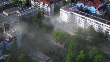 Sarı kurtarma helikopteri dumanlı bir acil durum sırasında Berlin şehir parkına iniyor. İHA kamerası aşağıya bakıyor 