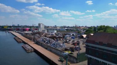 Hurda metal geri dönüşüm fabrikasının nehir limanındaki atıkları yöneten, mavnaları yükleyen hava görüntüsü. Ters İHA uçuşu 