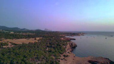 İspanya, İbiza 'da gün batımında deniz kıyısında tarihi bir kule manzarası. Ters İHA uçuşu 