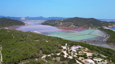 Önünde Akdeniz bitkisi olan İbiza 'nın renkli tuz düzlüklerinin havadan görünüşü. İHA alçalıyor 