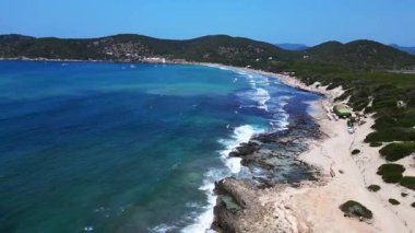 Turkuaz dalgalar ses Salines sahilinin kayalık sahillerine antik gözetleme kulesiyle çarpıyor. Ters İHA uçuşu 