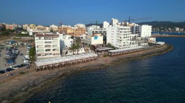 Turistler yaz tatillerini San Antonio Körfezi, İbiza 'da ünlü bir bar olan Cafe del Mar' da geçiriyorlar. panorama genel görünüm dronu 