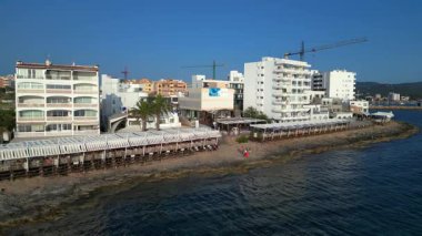 Turistler yaz tatillerini San Antonio Körfezi, İbiza 'da ünlü bir bar olan Cafe del Mar' da geçiriyorlar. Yukarıdan insansız hava aracı görüntüleri 