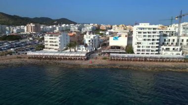 Turistler yaz tatillerini San Antonio Körfezi, İbiza 'da ünlü bir bar olan Cafe del Mar' da geçiriyorlar. panorama yörünge dronu 