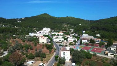 İspanya 'nın İbiza kentindeki Sant Joan de Labritja' da, güneşli bir yaz gününde geleneksel beyaz kilise, evler, yollar, dağlar ve yemyeşil alanlar yer alıyor. hız rampası hiper hareket zaman aşımı 