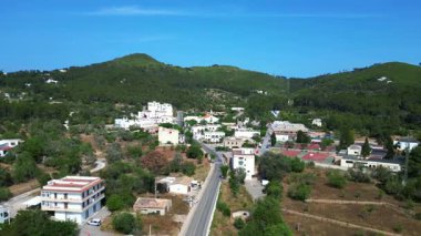 İspanya 'nın İbiza kentindeki Sant Joan de Labritja' da, güneşli bir yaz gününde geleneksel beyaz kilise, evler, yollar, dağlar ve yemyeşil alanlar yer alıyor. Ters İHA uçuşu 