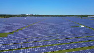 Sıralar halinde fotovoltaik güneş panelleri açık mavi gökyüzünün altındaki büyük bir enerji istasyonunda güneşi emiyor. İHA alçalıyor 