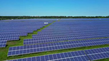 Sıralar halinde fotovoltaik güneş panelleri açık mavi gökyüzünün altındaki büyük bir enerji istasyonunda güneşi emiyor. uçuş üstü insansız hava aracı 