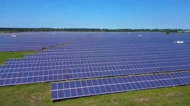 Sıralar halinde fotovoltaik güneş panelleri açık mavi gökyüzünün altındaki büyük bir enerji istasyonunda güneşi emiyor. Dolly sol İHA 