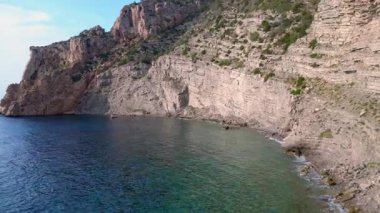 İspanya 'nın İbiza kentindeki bir körfezdeki kayaların arasından şeffaf turkuaz su akar. Yukarıdan insansız hava aracı görüntüleri 