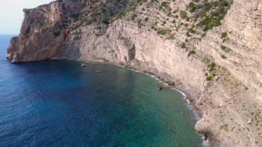 İspanya 'nın İbiza kentindeki bir körfezdeki kayaların arasından şeffaf turkuaz su akar. Drone 'u yukarı eğ 
