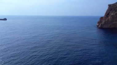 İspanya 'nın İbiza kentindeki bir körfezdeki kayaların arasından şeffaf turkuaz su akar. panorama genel görünüm dronu 