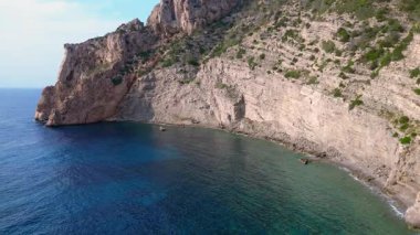 İspanya 'nın İbiza kentindeki bir körfezdeki kayaların arasından şeffaf turkuaz su akar. Ters İHA uçuşu 