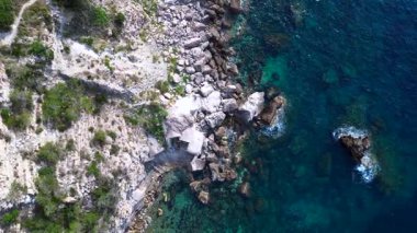 İspanya, İbiza 'nın kayalık sahillerinde kristal suyun havadan görünüşü. İHA kamerası aşağıya bakıyor 
