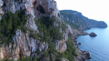 İspanya, İbiza 'nın kayalık sahillerinde kristal suyun havadan görünüşü. İHA alçalıyor 