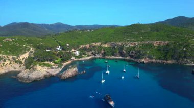 İspanya 'nın İbiza kentindeki yemyeşil bir körfezin turkuaz sularında demirlenmiş yelkenli ve yatların çarpıcı hava manzarası. hız rampası hiper hareket zaman aşımı 