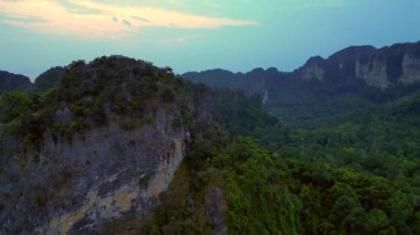 Alacakaranlıkta kireçtaşı uçurumları ve bereketli tropikal ormanlar Railay Sahili, Krabi, Tayland, dramatik ve sakin bir manzara yaratıyor. panorama genel görünüm dronu 