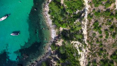 İbiza 'daki bir körfezde şeffaf turkuaz suda yüzen yelkenli ve yatların hava görüntüsü. Yukarıdan insansız hava aracı görüntüleri 