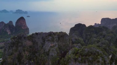 Alacakaranlıkta kireçtaşı uçurumları ve bereketli tropikal ormanlar Railay Sahili, Krabi, Tayland, dramatik ve sakin bir manzara yaratıyor. geniş yörünge görünümü dronu 