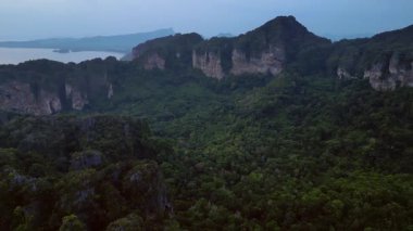 Alacakaranlıkta kireçtaşı uçurumları ve bereketli tropikal ormanlar Railay Sahili, Krabi, Tayland, dramatik ve sakin bir manzara yaratıyor. panorama genel görünüm dronu 