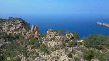 İspanya 'nın İbiza kentindeki kayalık bir uçurumda yürüyüş yapan bir grup turist, Akdeniz' in nefes kesici manzarasının tadını çıkarıyorlar. Yukarıdan insansız hava aracı görüntüleri 