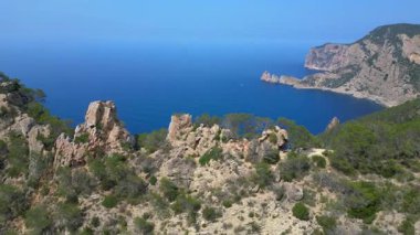 İspanya 'nın İbiza kentindeki kayalık bir uçurumda yürüyüş yapan bir grup turist, Akdeniz' in nefes kesici manzarasının tadını çıkarıyorlar. uçuş üstü insansız hava aracı 