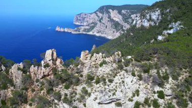 İspanya 'nın İbiza kentindeki kayalık bir uçurumda yürüyüş yapan bir grup turist, Akdeniz' in nefes kesici manzarasının tadını çıkarıyorlar. Üst uçuş panorama genel görünüm dronu 