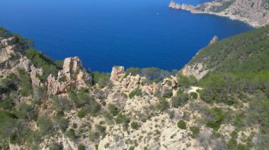 İspanya 'nın İbiza kentindeki kayalık bir uçurumda yürüyüş yapan bir grup turist, Akdeniz' in nefes kesici manzarasının tadını çıkarıyorlar. İHA kamerası aşağıya bakıyor 