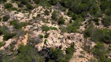 İspanya 'nın İbiza kentindeki kayalık bir uçurumda yürüyüş yapan bir grup turist, Akdeniz' in nefes kesici manzarasının tadını çıkarıyorlar. Drone 'u yukarı eğ 