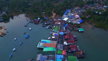 Bang Bao Pier, Koh Chang, Tayland 'da günbatımında sakin denizi yansıtan geleneksel stilt evlerin hava manzarası. İHA alçalıyor 