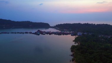 Tayland 'ın Koh Chang şehrinde günbatımında sakin suyu yansıtan geleneksel yüzen köyün hava manzarası. hız rampası hiper hareket zaman aşımı 