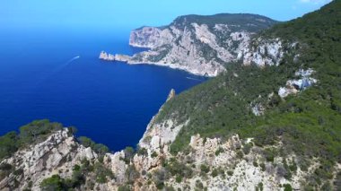 Kayalık kayalıkların ve yemyeşil bitki örtüsünün, İbiza kıyısındaki Akdeniz 'in engin genişliğiyle buluşması nefes kesici bir manzara. İHA alçalıyor 