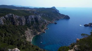 İbizas görkemli kayalıklarının ve turkuaz suların manzaralı manzarası Akdeniz güzelliğinin özünü yakalıyor. Çok yakından geçen bir insansız uçak 