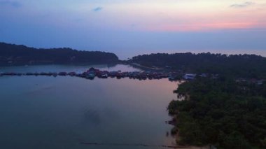 Tayland 'ın Koh Chang şehrinde günbatımında sakin suyu yansıtan geleneksel yüzen köyün hava manzarası. İHA alçalıyor 